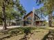 Exterior view of a log home with a stone chimney, porch, and lush surrounding trees at 2450 Flagami Ln, North Port, FL 34286