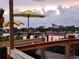 Scenic view of the waterfront with an American flag, captured from a wooden boardwalk with beach umbrellas at 250 Santa Maria St # 216, Venice, FL 34285