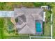 Birds-eye view of the home featuring a private screened pool, tile roof, well-manicured landscaping, and paved driveway at 4305 Sandune Ave, North Port, FL 34287