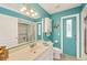 Bright bathroom with a shower, white cabinets, vanity, and a turquoise accent wall at 4305 Sandune Ave, North Port, FL 34287