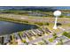 An aerial view of charming single-Gathering homes along a tranquil pond, with highway and water tower at 4835 San Ortebello Dr, Bradenton, FL 34208