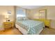 Bright bedroom with a patterned bedspread, yellow furniture, and a sunny window at 595 Circlewood Dr # Y4, Venice, FL 34293
