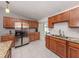 Well-lit kitchen with stainless steel refrigerator, granite countertops, and wooden cabinets at 8132 Coco Solo Ave, North Port, FL 34287