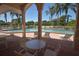 View from under the covered patio of the pool with lounge chairs and lush landscaping at 8300 Parkside Dr, Englewood, FL 34224
