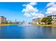 Scenic community lake view featuring a fountain and colorful buildings under a bright blue, partly cloudy sky at 8405 Placida Rd # 206, Placida, FL 33946
