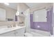 Bathroom featuring white vanity, tiled tub and shower, and decorative lavender wall accents at 938 The Rialto, Venice, FL 34285