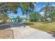 Exterior view of the property showcasing a spacious driveway and lush lawn and tropical foliage at 938 The Rialto, Venice, FL 34285
