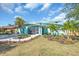 Charming home boasting a vibrant turquoise exterior, beautiful landscaping, and a screened porch with an American flag at 938 The Rialto, Venice, FL 34285
