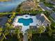 Aerial view of a community pool area surrounded by palm trees, lounge chairs and a community building at 27336 Driver Ln, Englewood, FL 34223