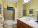 Bathroom with a shower and tub combo, a vanity, and yellow striped wallpaper at 27336 Driver Ln, Englewood, FL 34223