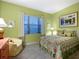 Comfortable bedroom with a window view, soft lighting, and patterned bedding at 27336 Driver Ln, Englewood, FL 34223