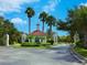 Community entrance features manicured landscaping, palm trees and charming guard house with a red tile roof at 27336 Driver Ln, Englewood, FL 34223
