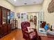 The home office boasts hardwood floors, a dark wood display case, and a comfortable leather chair with shell pillow at 27336 Driver Ln, Englewood, FL 34223