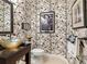 This powder room features leaf-patterned wallpaper, a vessel sink, and modern fixtures for a stylish design at 27336 Driver Ln, Englewood, FL 34223