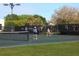 Active tennis court scene with two players, lush greenery, and the community name visible on the fence at 27336 Driver Ln, Englewood, FL 34223
