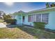 Charming exterior view of the light blue house featuring a well-kept lawn, and a quaint front entrance at 100 Aurora W St, Venice, FL 34285