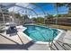 Outdoor pool area with sun loungers, table, chairs and a screened enclosure for leisure at 100 Aurora W St, Venice, FL 34285