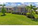 Home's screened lanai overlooks the beautifully landscaped backyard with lush green grass, trees and shrubs at 11026 Barnsley Dr, Venice, FL 34293