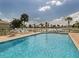 Inviting community pool with lounge chairs, umbrellas, and a scenic view of the neighborhood pond at 11026 Barnsley Dr, Venice, FL 34293