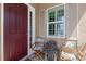Charming front porch with a red door, shuttered window and outdoor seating at 11026 Barnsley Dr, Venice, FL 34293