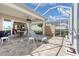 Relaxing screened-in lanai with patterned pavers, dining area, lounge chair and view to adjacent home and blue skies at 11026 Barnsley Dr, Venice, FL 34293