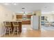 View of open kitchen with wood cabinets, tile flooring, and breakfast bar adjoining to the living area at 11153 Deerwood Ave, Englewood, FL 34224