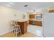 Open kitchen with wooden cabinets, tile flooring, breakfast bar, and stainless steel appliances at 11153 Deerwood Ave, Englewood, FL 34224