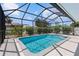 Beautiful in-ground pool with screened enclosure, lush landscaping, and sunny skies overhead at 11153 Deerwood Ave, Englewood, FL 34224