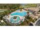 An aerial view reveals a luxurious pool area with lounge chairs, palm trees, and well manicured landscaping at 115 Babbling Brook Run, Bradenton, FL 34212