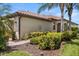 Beige one-story home featuring a clay tile roof, lush landscaping, and a brick walkway at 115 Babbling Brook Run, Bradenton, FL 34212