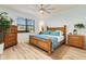 Bright bedroom with light wood floors, blue accents, and a window view of the lush outdoors at 115 Babbling Brook Run, Bradenton, FL 34212