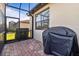 Screened-in patio area with brick flooring, grill, and view of the lush landscaping at 115 Babbling Brook Run, Bradenton, FL 34212