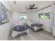 Bright bedroom with two twin beds, featuring neutral decor, hardwood floors, and natural light from the windows at 1232 Pine Needle Rd, Venice, FL 34285