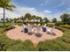 Outdoor fire pit surrounded by white Adirondack chairs, set on a brick patio with lush landscaping and palm trees at 13166 Huerta St, Venice, FL 34293