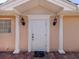 Inviting front entrance with a classic white door, columns, and decorative lighting fixtures at 13166 Huerta St, Venice, FL 34293