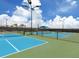 Multiple tennis courts with blue and green surfaces, enclosed by a black fence under a bright sunny sky at 13166 Huerta St, Venice, FL 34293