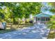 Charming cottage exterior with screened-in porch, lush landscaping, and long driveway at 140 Avenida De La Isla, Nokomis, FL 34275