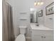 Clean bathroom with a toilet, sink, mirror, and tiled shower with curtain at 15232 Faulkner Ave, Port Charlotte, FL 33953