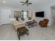 Bright living room featuring neutral walls, tile floors, modern furniture, and large TV at 15232 Faulkner Ave, Port Charlotte, FL 33953