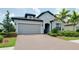 Attractive single-story home with a brick driveway, side entry garage, and manicured landscaping at 1565 Hyssop Loop, North Port, FL 34289