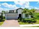 Charming single-story home with a brick driveway, lush landscaping, and a gray tiled roof at 1565 Hyssop Loop, North Port, FL 34289