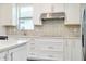 Kitchen featuring stainless steel hood vent over cooktop and light brick backsplash at 1565 Hyssop Loop, North Port, FL 34289