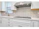 Kitchen featuring stainless steel hood vent over cooktop and light brick backsplash and quartz countertops at 1565 Hyssop Loop, North Port, FL 34289