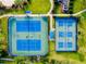 Aerial view of pristine tennis courts with manicured landscaping and vibrant blue playing surfaces at 1565 Hyssop Loop, North Port, FL 34289