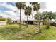 Expansive backyard features multiple palm trees and a well-maintained lawn, and a partial view of the home at 1609 Kirkwood St, North Port, FL 34288