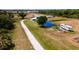 Aerial view showcasing a property with long driveway, pond, house, recreational vehicle, and wooded areas at 1727 E Manasota Beach Rd, Englewood, FL 34223