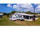 Exterior view featuring a well-maintained home, lush lawn, multiple parked vehicles, and serene surroundings at 1727 E Manasota Beach Rd, Englewood, FL 34223