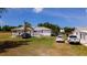 Wide exterior shot of a charming home featuring a well-kept lawn, a palm tree, and multiple parked vehicles at 1727 E Manasota Beach Rd, Englewood, FL 34223