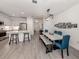 Open dining area with modern light fixture, long table with upholstered chairs, and easy access to the kitchen at 18002 Franklin Park Ct, Venice, FL 34293