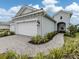 Charming single-Gathering home featuring a two-car garage, a brick driveway, and lush landscaping, presenting a welcoming curb appeal at 18002 Franklin Park Ct, Venice, FL 34293